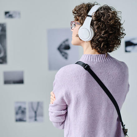 Museum visitor viewing an exhibit with an audio guide.